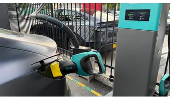比亞迪閃充青綠色充電槍經 v.NEXT-mini 轉接頭連接 Tesla，旁為閃充充電樁