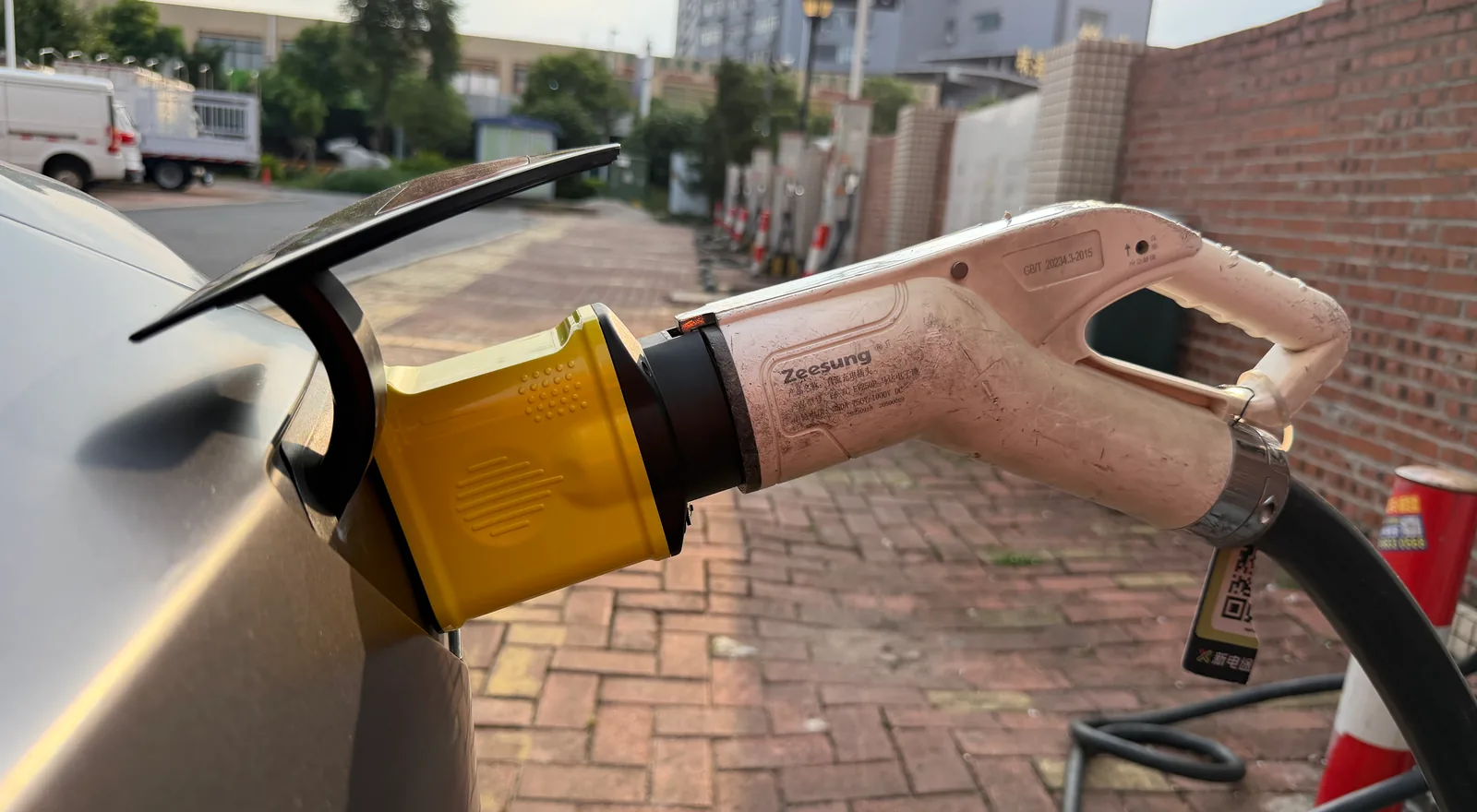 萬城萬充白色國標充電槍經黃色 v.NEXT-mini 轉接頭接駁車輛充電口的近照
